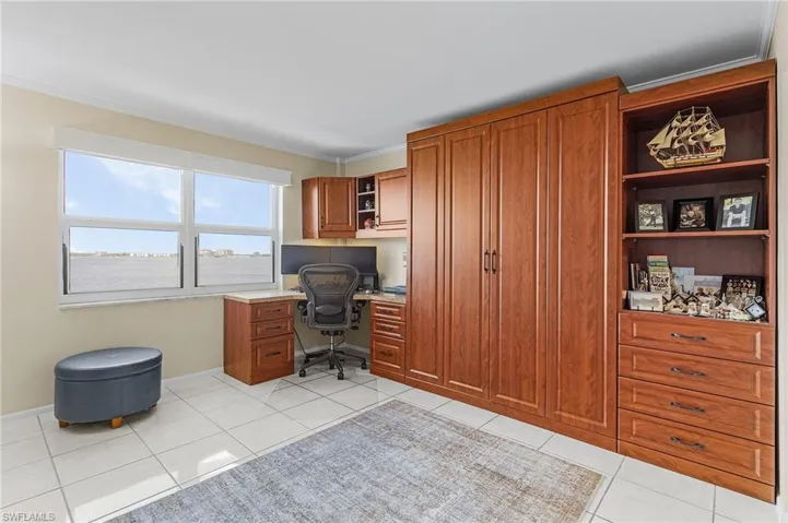 Office with built in desk, light tile patterned flooring, baseboards, and ornamental molding