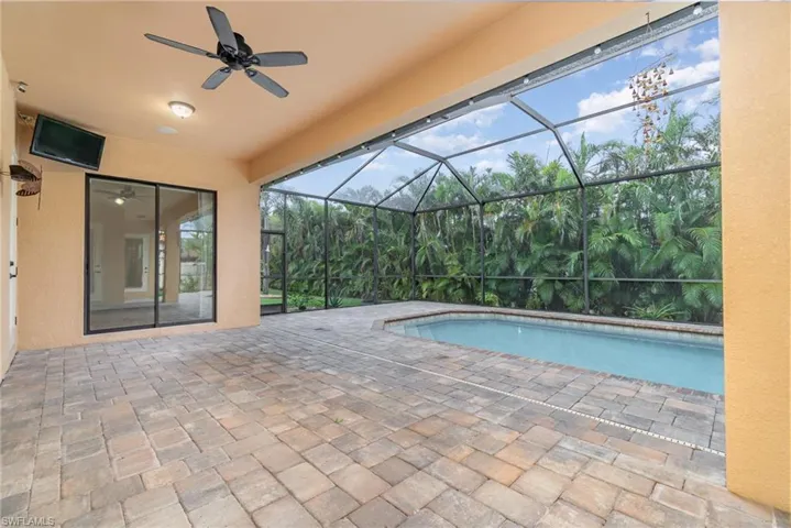 View of pool with screen enclosure and a patio area