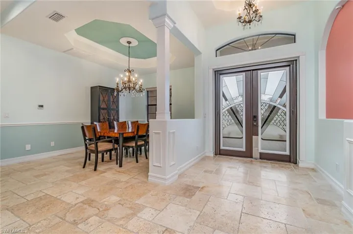 Foyer entrance featuring a tray ceiling, stone floors  nd impact front door