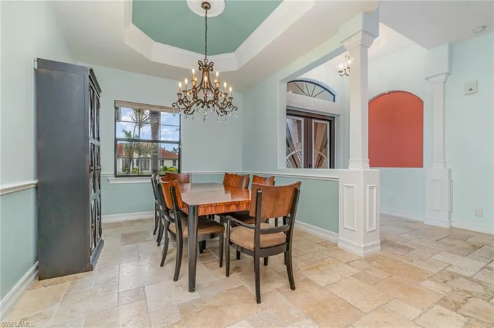 Dining area featuring a chandelier, a tray ceiling, decorative columns, and ornamental molding
