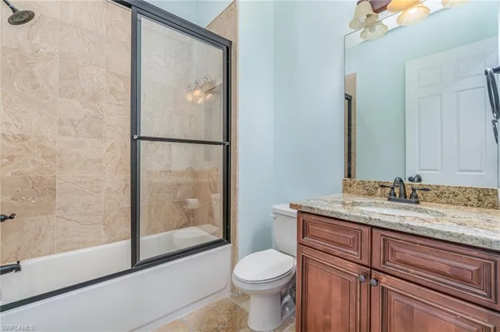 Guest  bathroom featuring shower / bath combination with glass door, vanity, and toilet
