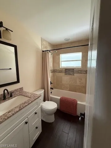 Full bathroom featuring hardwood / wood-style flooring, shower / bath combo, toilet, and vanity