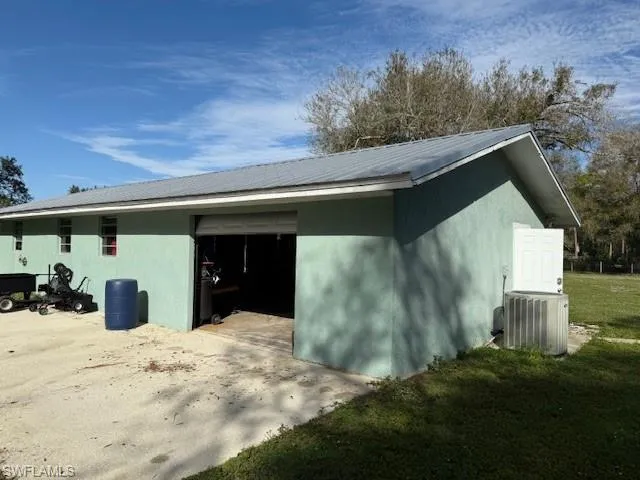 View of side of property featuring a lawn and cooling unit