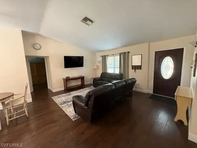 Living room featuring vaulted ceiling and dark wood-type flooring