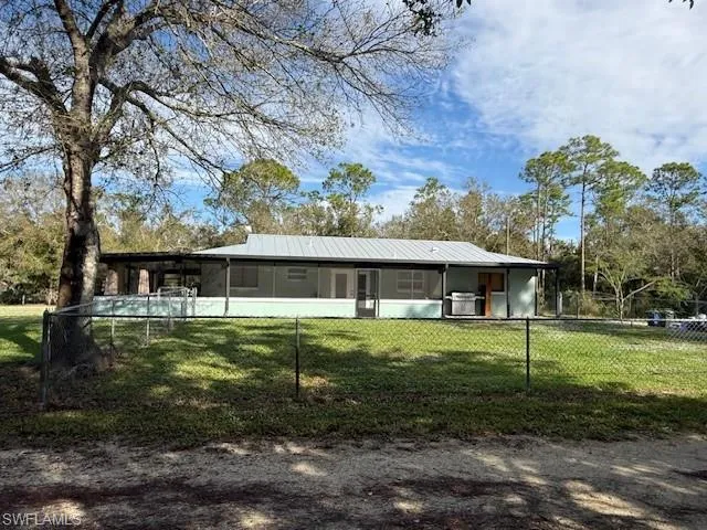 Back of house featuring a lawn and a sunroom