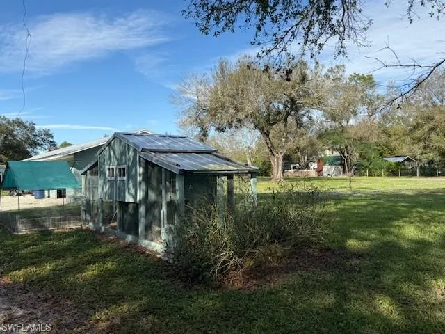 View of outbuilding featuring solar panels and a yard