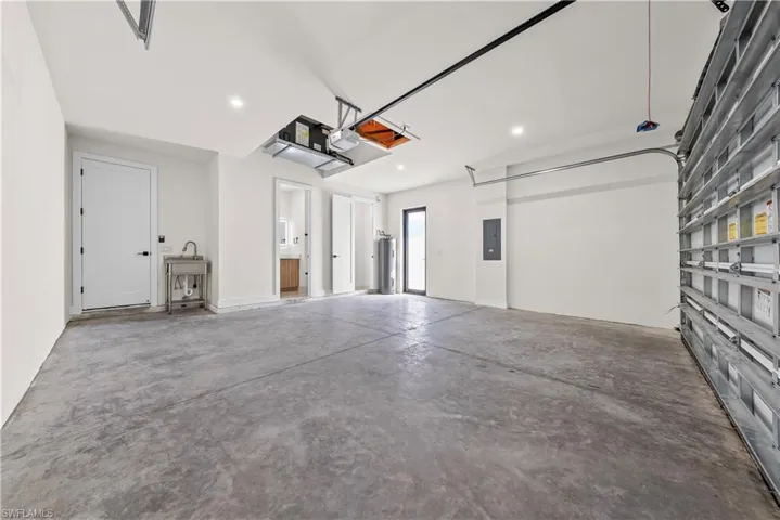 Garage featuring electric panel, a garage door opener, and recessed lighting