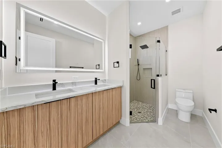 Full bathroom featuring double vanity, a stall shower, light tile patterned floors, and recessed lighting
