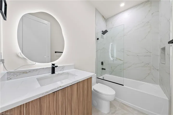 Bathroom with washtub / shower combination, vanity, and recessed lighting