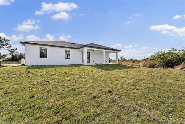 View of front of property with a ceiling fan, a front yard, stucco siding, and a patio area
