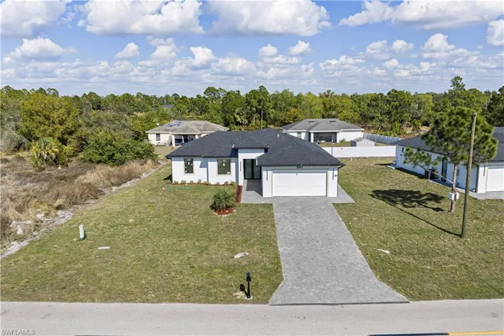 View of front of property featuring a front yard, decorative driveway, roof with shingles, and an attached garage