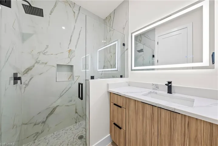 Bathroom with vanity and a marble finish shower