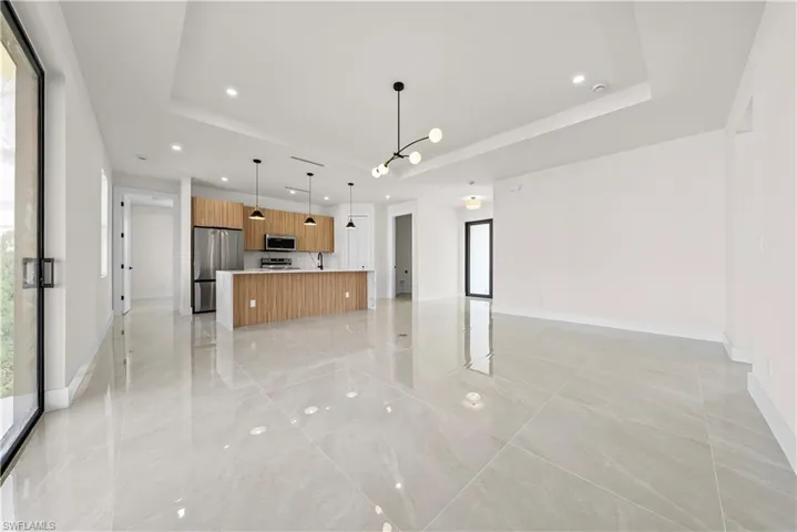 Unfurnished living room featuring a raised ceiling and recessed lighting