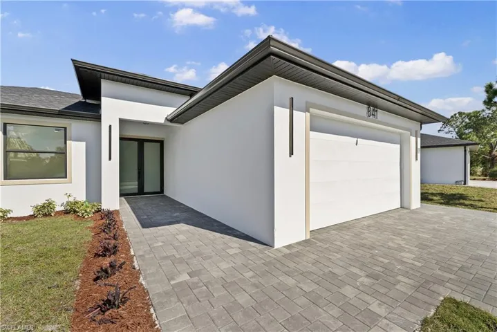 View of front of property featuring stucco siding, a front lawn, decorative driveway, a garage, and roof with shingles