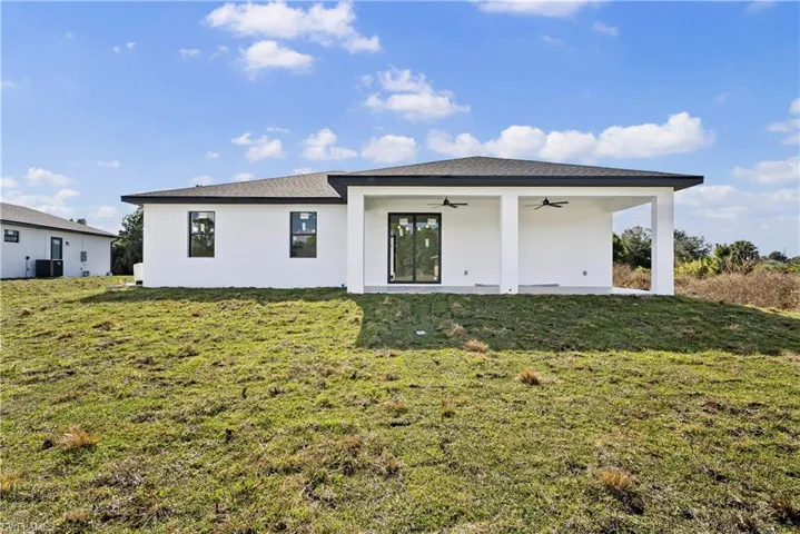 Back of property featuring a ceiling fan, a yard, stucco siding, and a patio