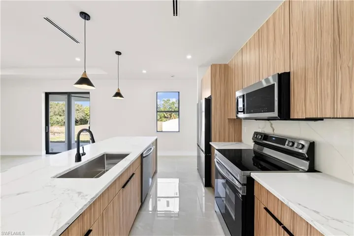 Kitchen with modern cabinets, light stone counters, and stainless steel appliances