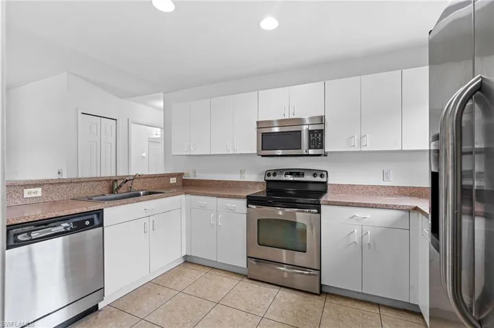 Kitchen featuring stainless steel appliances, white cabinets, light tile patterned floors, a peninsula, and recessed lighting
