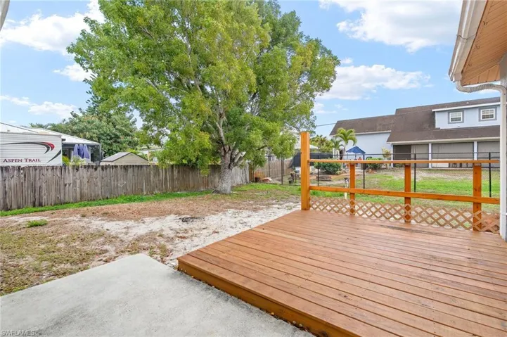 Wooden terrace with a fenced backyard