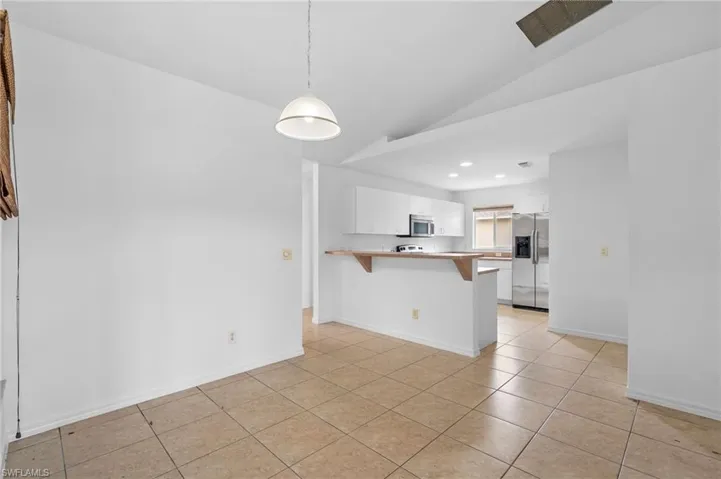 Kitchen with a breakfast bar area, a peninsula, light countertops, stainless steel appliances, and hanging light fixtures