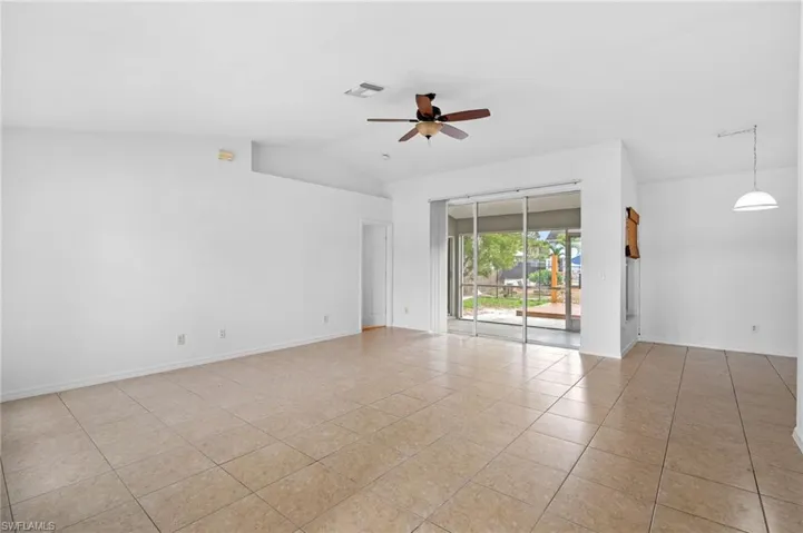 Unfurnished room featuring ceiling fan, lofted ceiling, and light tile patterned flooring