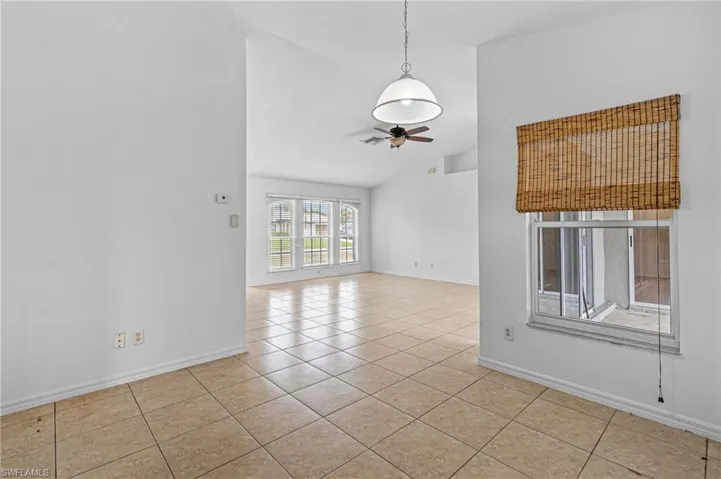 Empty room featuring vaulted ceiling, ceiling fan, and light tile patterned flooring