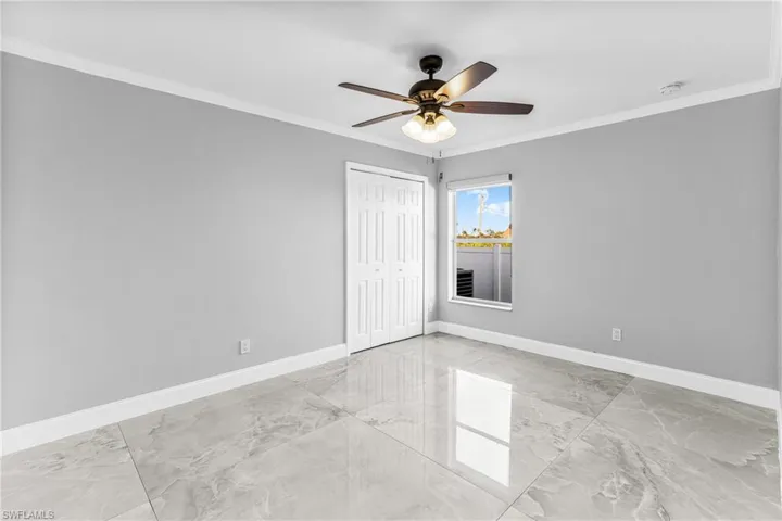 Empty room with ceiling fan and crown molding