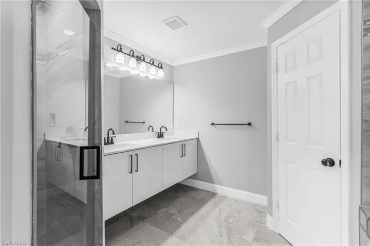 Bathroom featuring walk in shower, vanity, and ornamental molding
