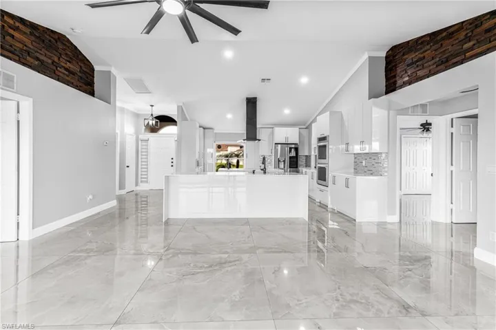 Unfurnished living room with high vaulted ceiling and ceiling fan