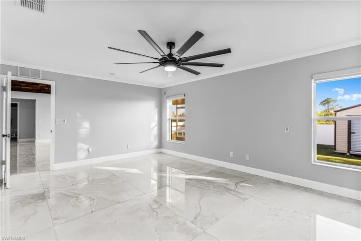 Empty room featuring ceiling fan, a healthy amount of sunlight, and ornamental molding