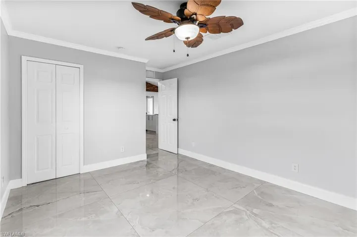 Unfurnished bedroom with ceiling fan, a closet, and ornamental molding