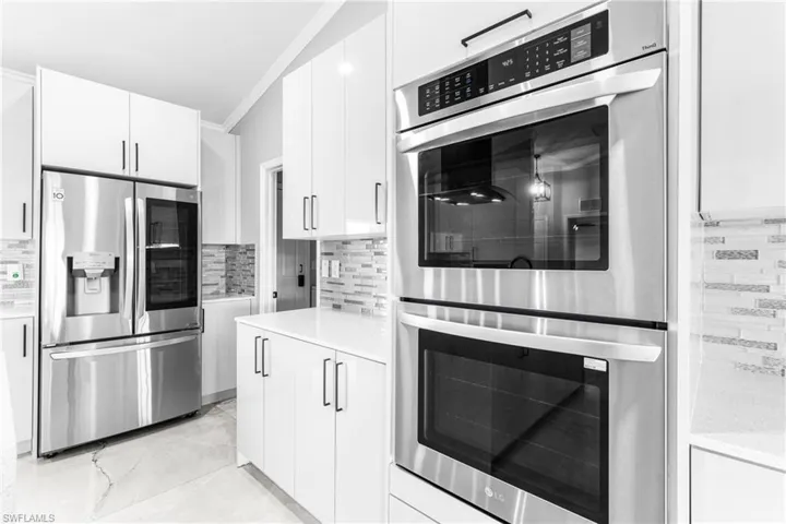Kitchen featuring tasteful backsplash, white cabinetry, ornamental molding, and stainless steel appliances
