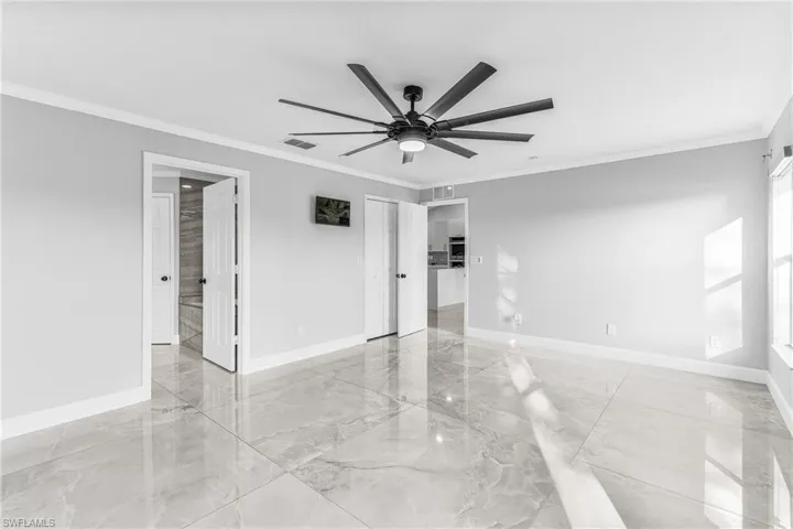 Empty room featuring ceiling fan and crown molding