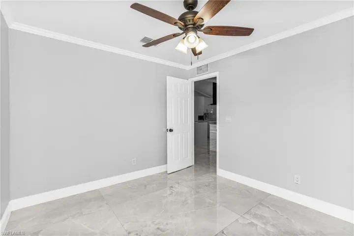Unfurnished room featuring ceiling fan and crown molding