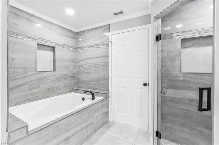Bathroom featuring independent shower and bath and crown molding