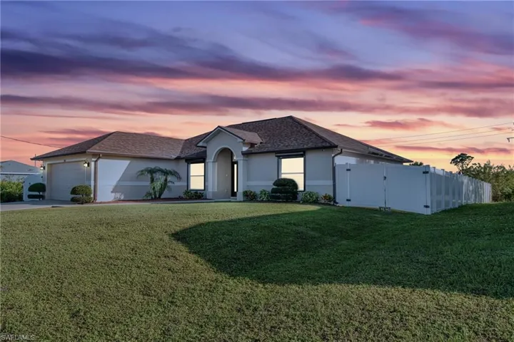 View of front of home with a garage and a lawn