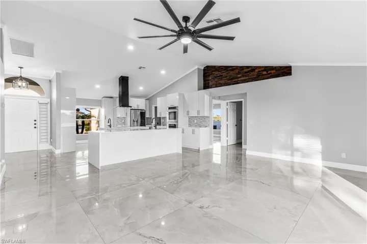 Unfurnished living room with high vaulted ceiling, ceiling fan, and crown molding