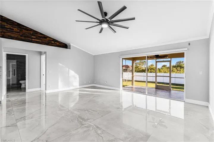 Empty room featuring vaulted ceiling, ceiling fan, and crown molding