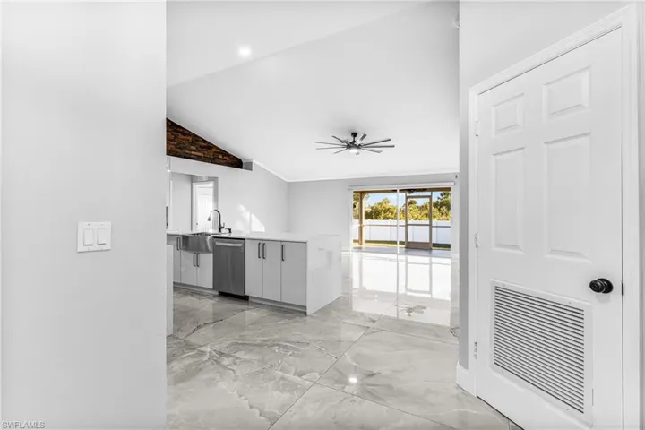 Kitchen with white cabinetry, vaulted ceiling, stainless steel dishwasher, kitchen peninsula, and ceiling fan