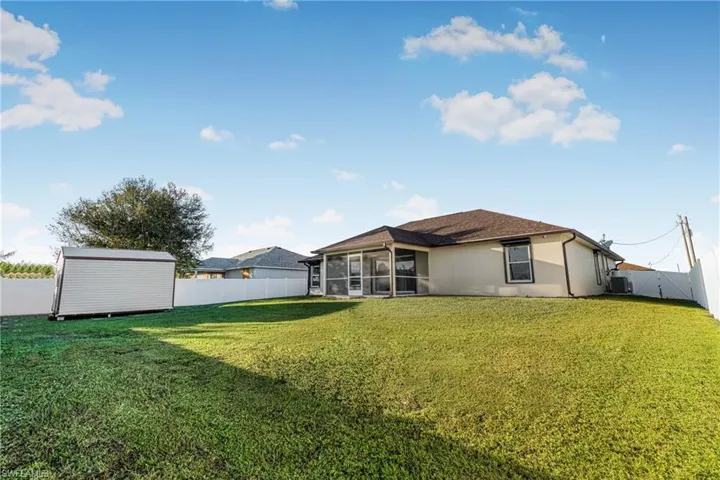 Rear view of house featuring a shed, a lawn, and a sunroom