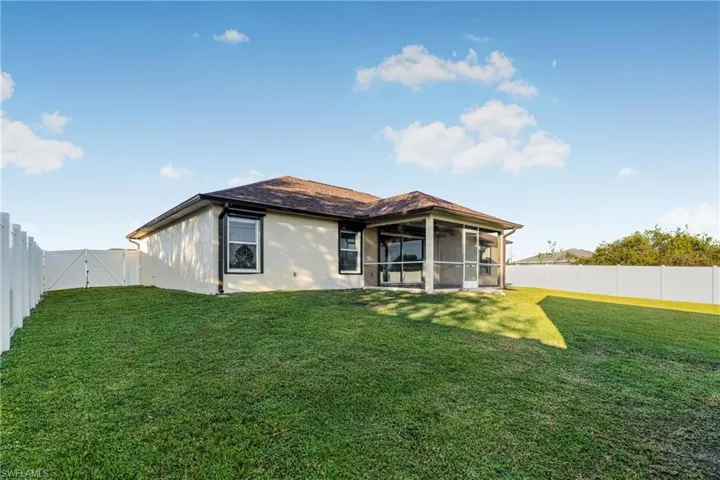 Back of property with a lawn and a sunroom