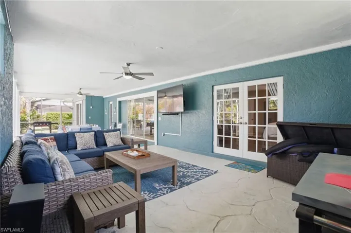 Living area featuring concrete floors, a textured wall, ceiling fan, and french doors