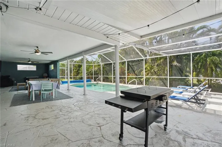 Outdoor pool with glass enclosure, outdoor dining area, a ceiling fan, and a patio area