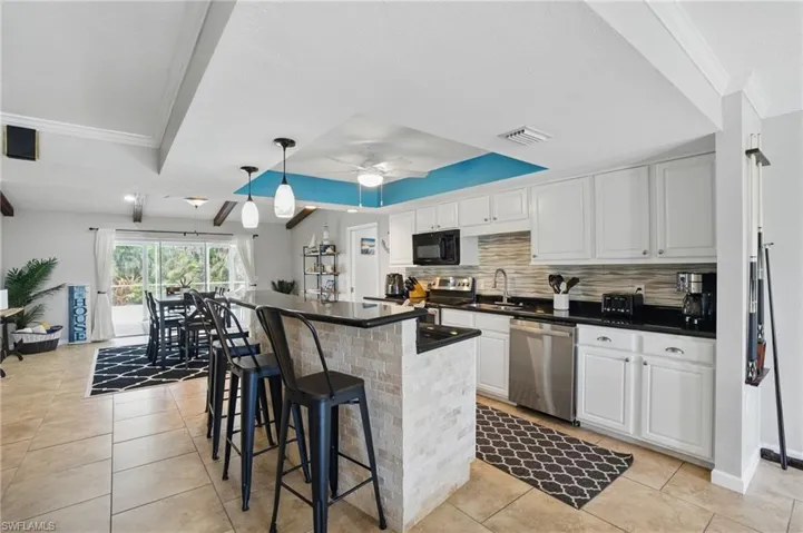 Kitchen with stainless steel appliances, a sink, dark countertops, and crown molding
