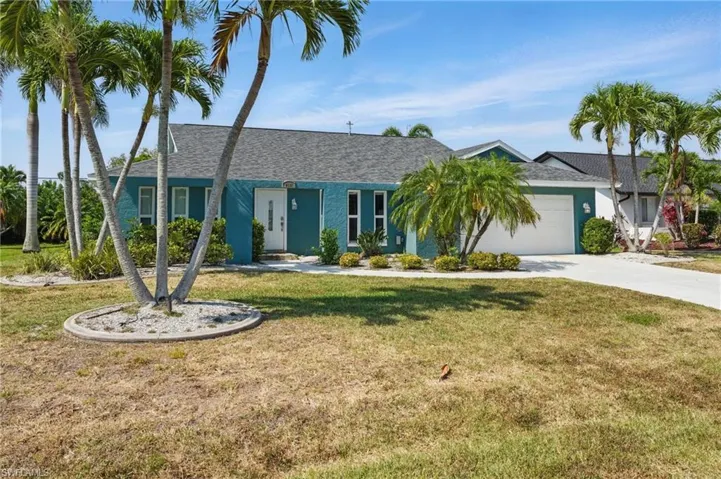 Single story home featuring concrete driveway, an attached garage, roof with shingles, and a front yard
