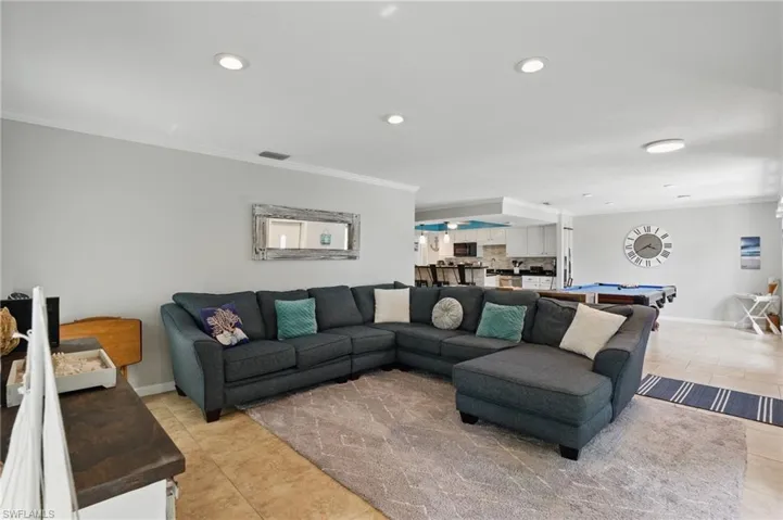 Living area with recessed lighting, visible vents, ornamental molding, and light tile patterned floors