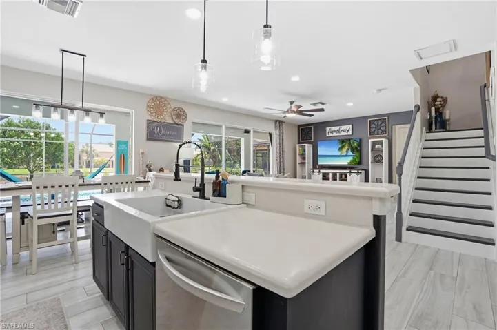 Modern kitchen featuring a farmhouse sink with a matte black faucet, light countertops, and dark cabinetry