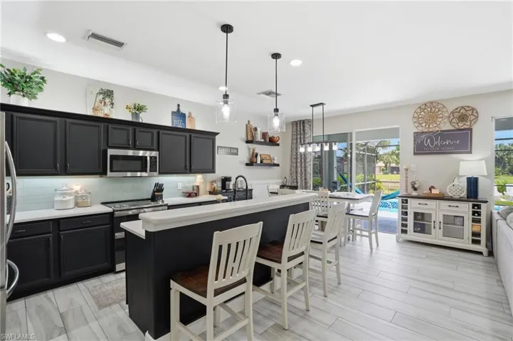 Open-concept kitchen featuring dark cabinetry, light countertops, and light wood-finish flooring