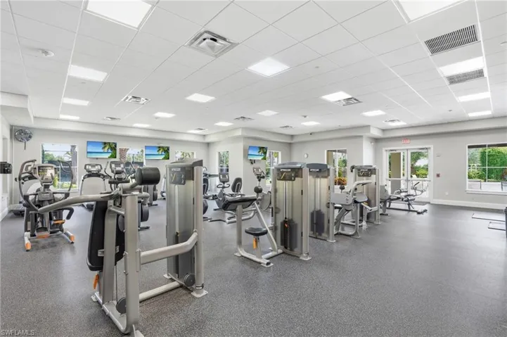 Spacious fitness center featuring a drop ceiling with recessed lighting, light gray painted walls, and dark gray rubber flooring