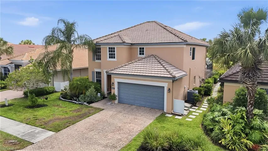 Two-story residence featuring a tile roof, an integrated garage with a neutral-toned door, and mature landscaping