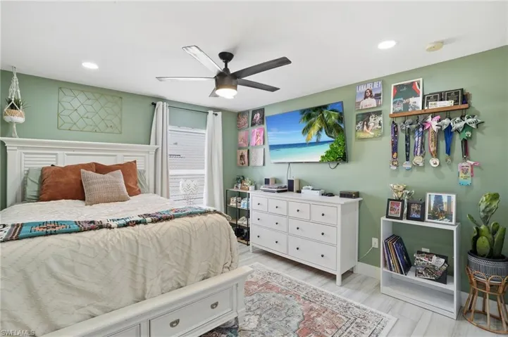 Spacious bedroom featuring light green walls, a ceiling fan with integrated lighting, recessed lighting, wood-finish flooring, and a large window